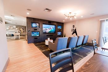 A living room with chairs and a table and a television